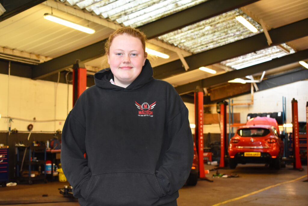Motor vehicle apprentice Chloe standing in a garage.