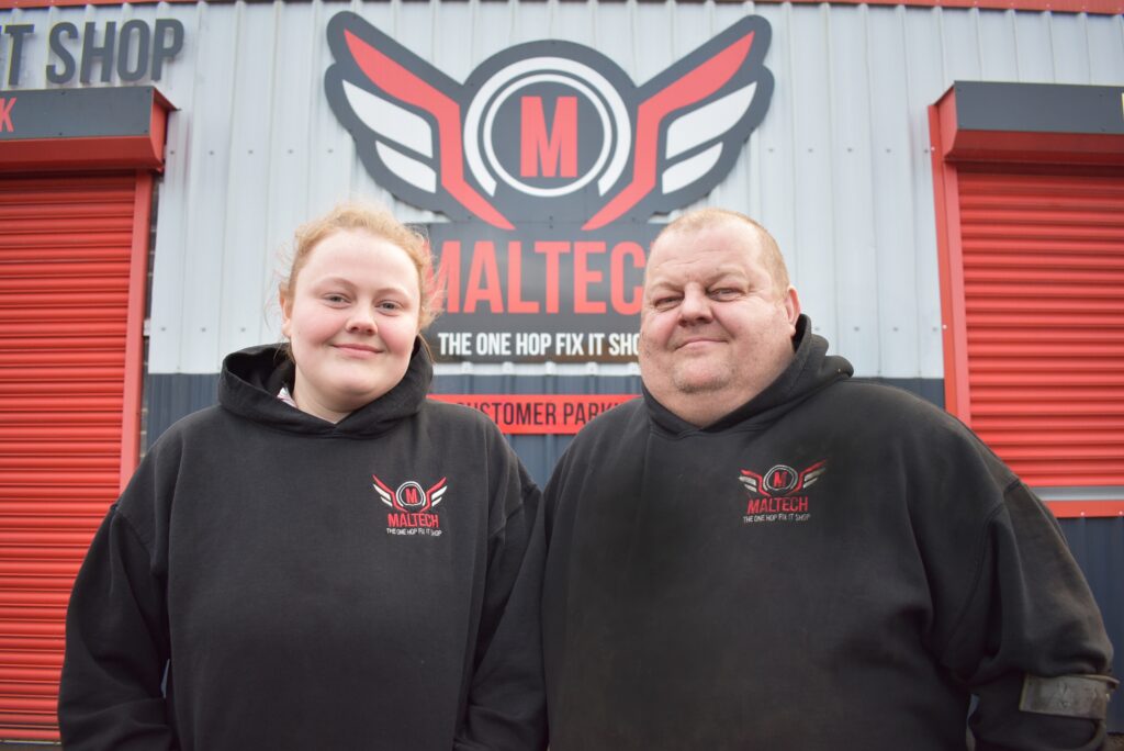 Motor vehicle apprentice Chloe and her dad in front of the garage.