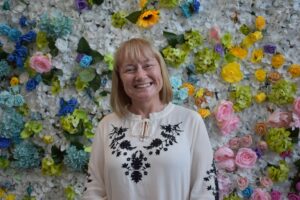 Fiona Sharp standing in front of a flower wall.