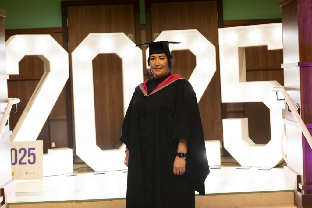 Student dressed in graduation gown with 2025 in lights