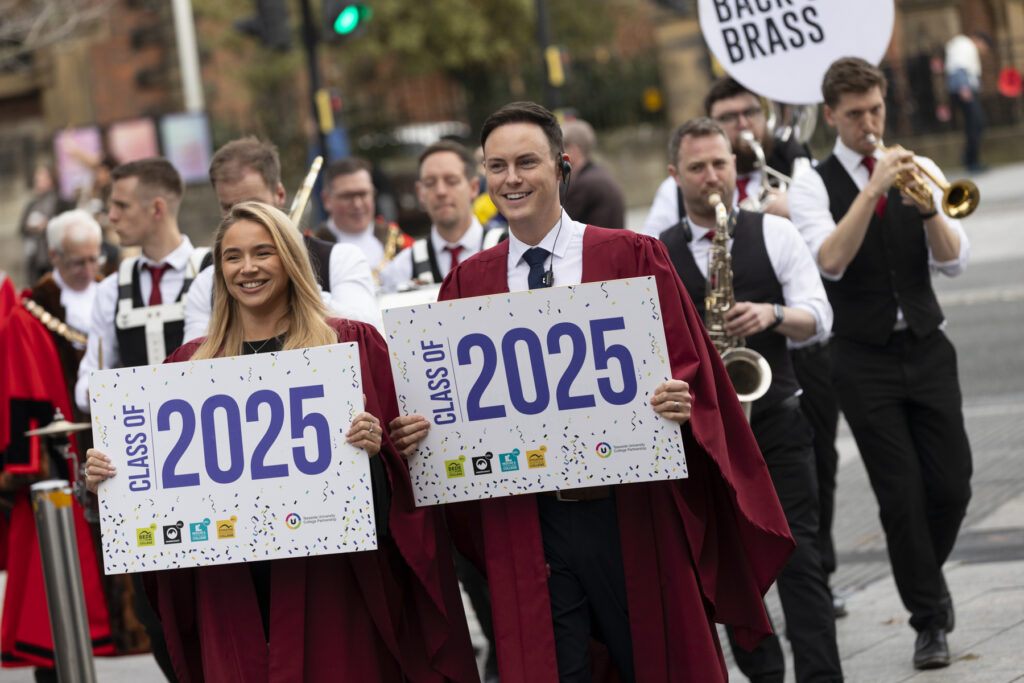 Two college staff members lead graduation procession