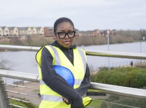 Celine stands in high vis and helmet on Stockton Infinity Bridge
