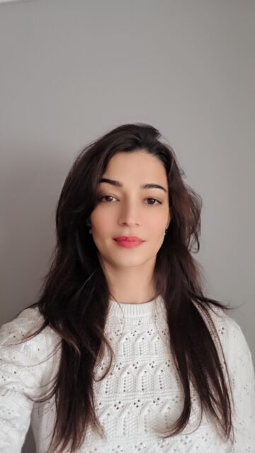 a person with a white jumper and long dark hair takes a selfie