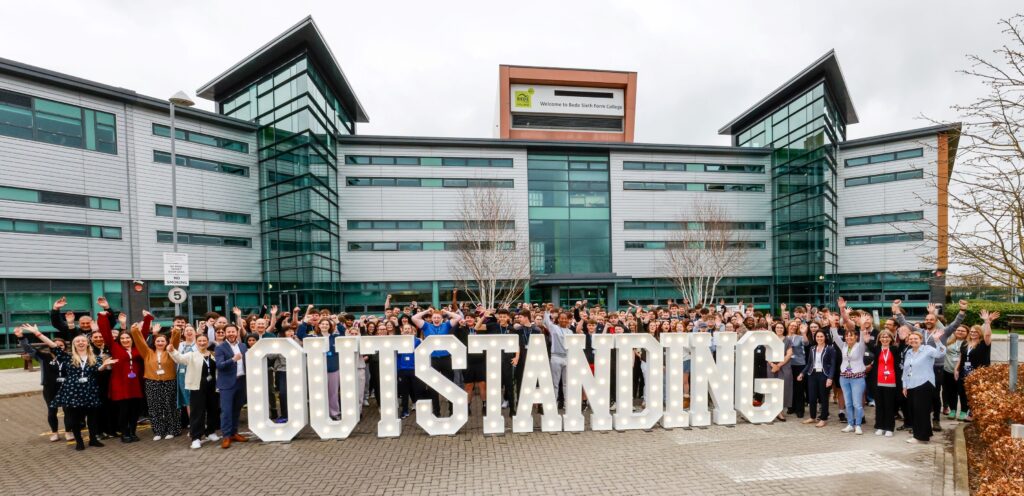 Staff and students outside Bede Sixth Form College with Outstanding sign