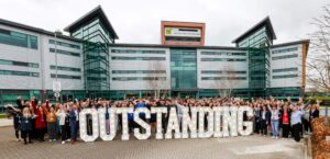 Staff and students outside Bede Sixth Form College with Outstanding sign