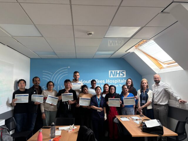 A group of people holding certificates smiling at the camera